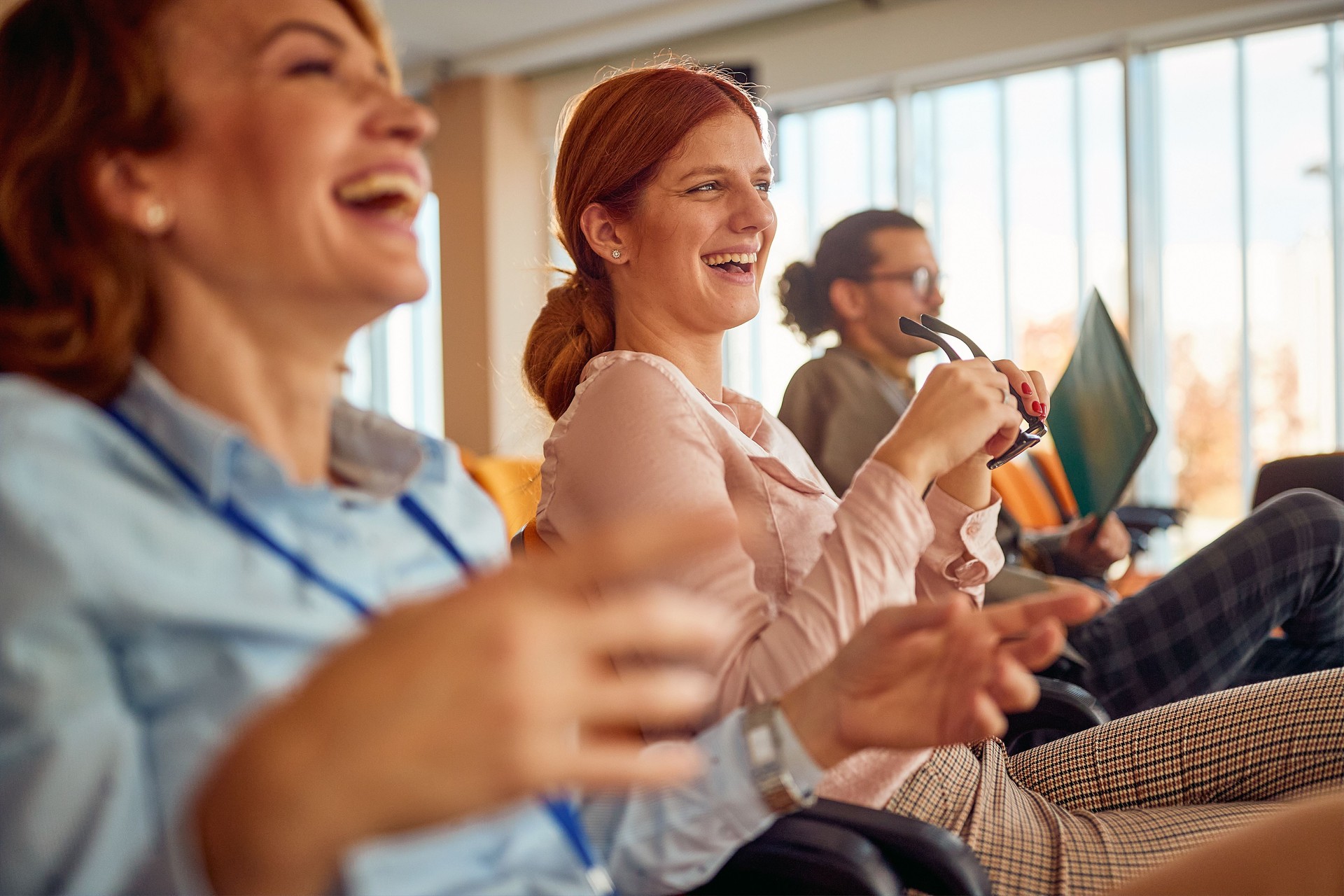 Two cheerful female colleagues having fun during a business lecture in the conference room. Business, people, company